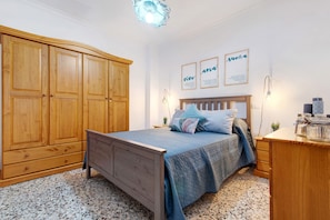 Un dormitorio con un armario de madera, una cama con colcha azul y dos carteles motivacionales enmarcados en la pared.