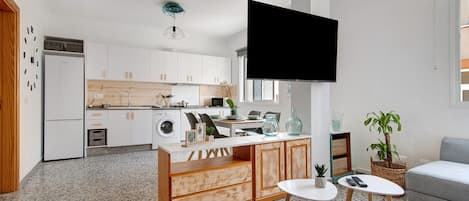 A modern kitchen with white cabinets, a wooden island, and a flat-screen TV mounted above the island.