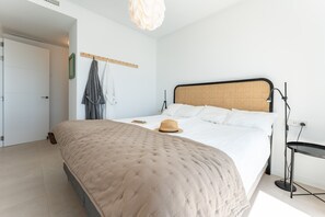 A bedroom with a bed, a hat on the bed, a standing lamp, and a door.