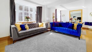 A modern living room with two sofas, a dining area, and a large mirror. - Spacious Knightsbridge Apartment Near Harrods (London)