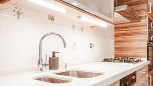 Uma cozinha moderna com bancada comprida, cuba de aço inoxidável e fogão embutido.