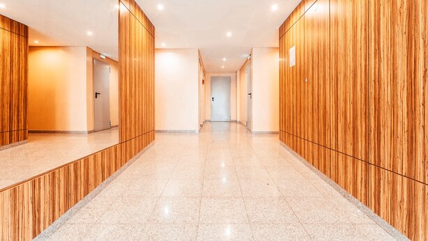 Um corredor moderno com lambris de madeira e chão de azulejos polidos.