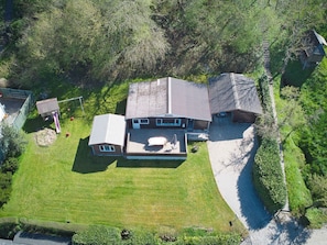Une maison à deux étages, dotée d’un toit en pente, d’un patio couvert et d’une pelouse bien entretenue.