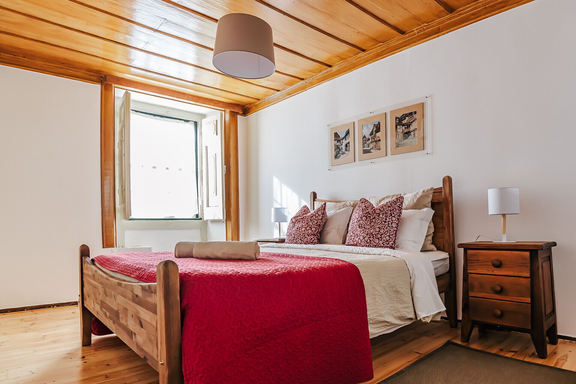 A bedroom with a wooden bed, a nightstand, and a window.