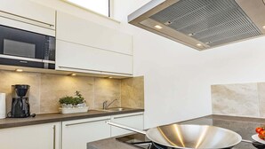 Cozinha moderna com micro-ondas embutido, cafeteira e fogão.