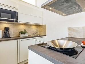 A modern kitchen with a built-in microwave, a coffee maker, and a stove.