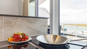 Cozinha moderna com uma janela grande, uma panela de aço inoxidável e um prato de frutas.
