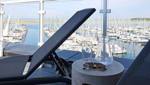 A balcony with a view of a marina, a glass pitcher, and a pair of glasses on a table. - 5 Star Holiday Home in Wendtorf (Wendtorf)