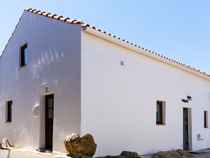 A modern building with a white facade, red-tiled roof, and multiple windows.