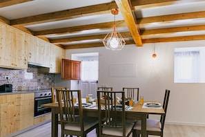 A kitchen with wooden cabinets, a dining table with chairs, and a hanging light fixture.