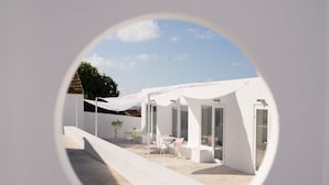 A modern outdoor patio with white furniture and a glass door entrance. - CASASUPERTUBOS - APART T1 (Atouguia da Baleia)