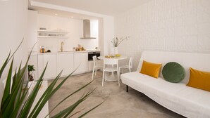 Eine moderne Küche mit weißen Schränken, einem weißen Esstisch und einem weißen Sofa mit gelben Kissen.