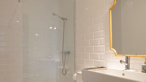 A modern bathroom with a glass shower enclosure, a white toilet, and a vanity with a gold-framed mirror.