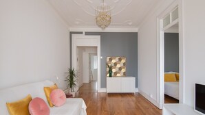 Una sala de estar moderna con un sofá blanco, piso de madera y un adorno de pared decorativo.