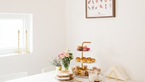 Una mesa blanca con pastel, pasteles y bebidas.