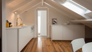 A modern kitchen with white cabinetry, a wooden floor, and a skylight. - CASASUPERTUBOS - APART 14 (Peniche)