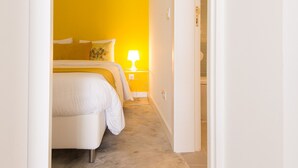 A narrow hallway leading to a bedroom with a bed, bedside table, and a lamp. - CASASUPERTUBOS - APART 11 (Peniche)