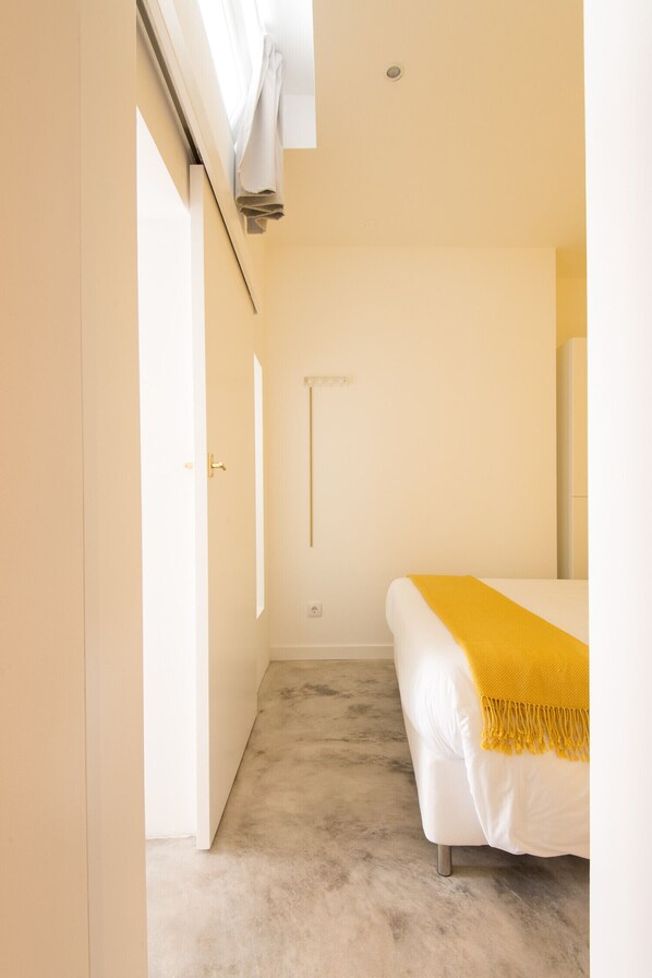A bedroom with a bed, a door, and a window.