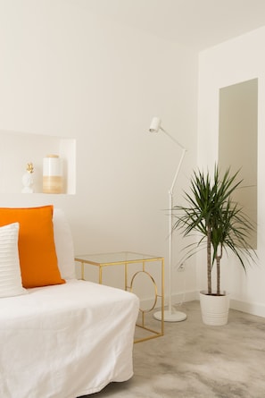 Une chambre à coucher comprenant un lit, une table de chevet, une lampe, une plante en pot et une étagère murale décorée de divers objets.
