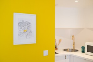 A kitchen with a white countertop, a stainless steel sink, and a gold faucet.