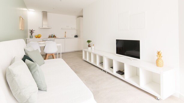 Ett modernt vardagsrum med en vit soffa, en platt-TV och en minimalistisk design.