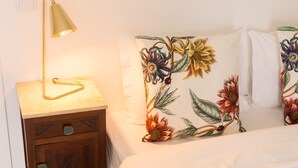 Ett sovrum med en säng, ett nattduksbord med en lampa och en sänggavel med ett blommönster.