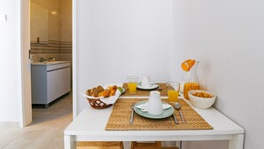 Colazione con croissant, succo d'arancia e cereali su un tavolo bianco con un sottopiattino di vimini.