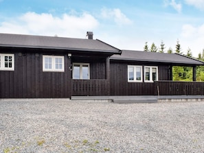 A two-story wooden building with a gravel driveway and a covered porch.