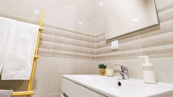 A bathroom with a white sink, a mirror, a towel rack, and a small plant.