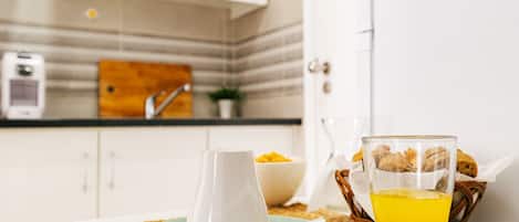 A breakfast setting with a pitcher, a glass of orange juice, and a bowl of fruit on a woven mat.