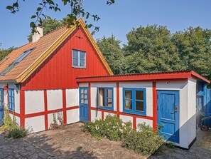 A red and white building with a sloped roof and a small attached structure with blue doors.