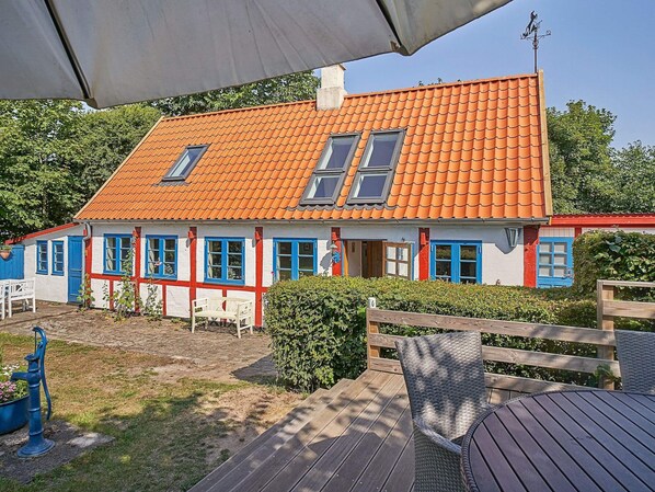 A house with a red-tiled roof, white walls, and blue doors and windows.
