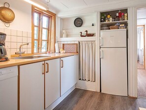 A kitchen with white cabinets, a wooden countertop, a sink, a coffee maker, a clock, and a refrigerator. - 6 Person Holiday Home in Aakirkeby (Akirkeby)