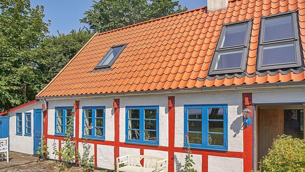 A traditional house with a red-tiled roof, white walls, and blue-framed windows. - 6 Person Holiday Home in Aakirkeby (Akirkeby)