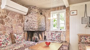 A stone fireplace with a bench seating area, a wooden table, and a window with a view of greenery. - 6 Person Holiday Home in Aakirkeby (Akirkeby)