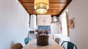 Un coin repas avec une table, des chaises, une plante en pot et une cuisine en arrière-plan.