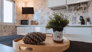 A kitchen with a microwave, coffee maker, and a potted plant on a wooden tray. - Encosta d'Óbidos T1 (Óbidos)