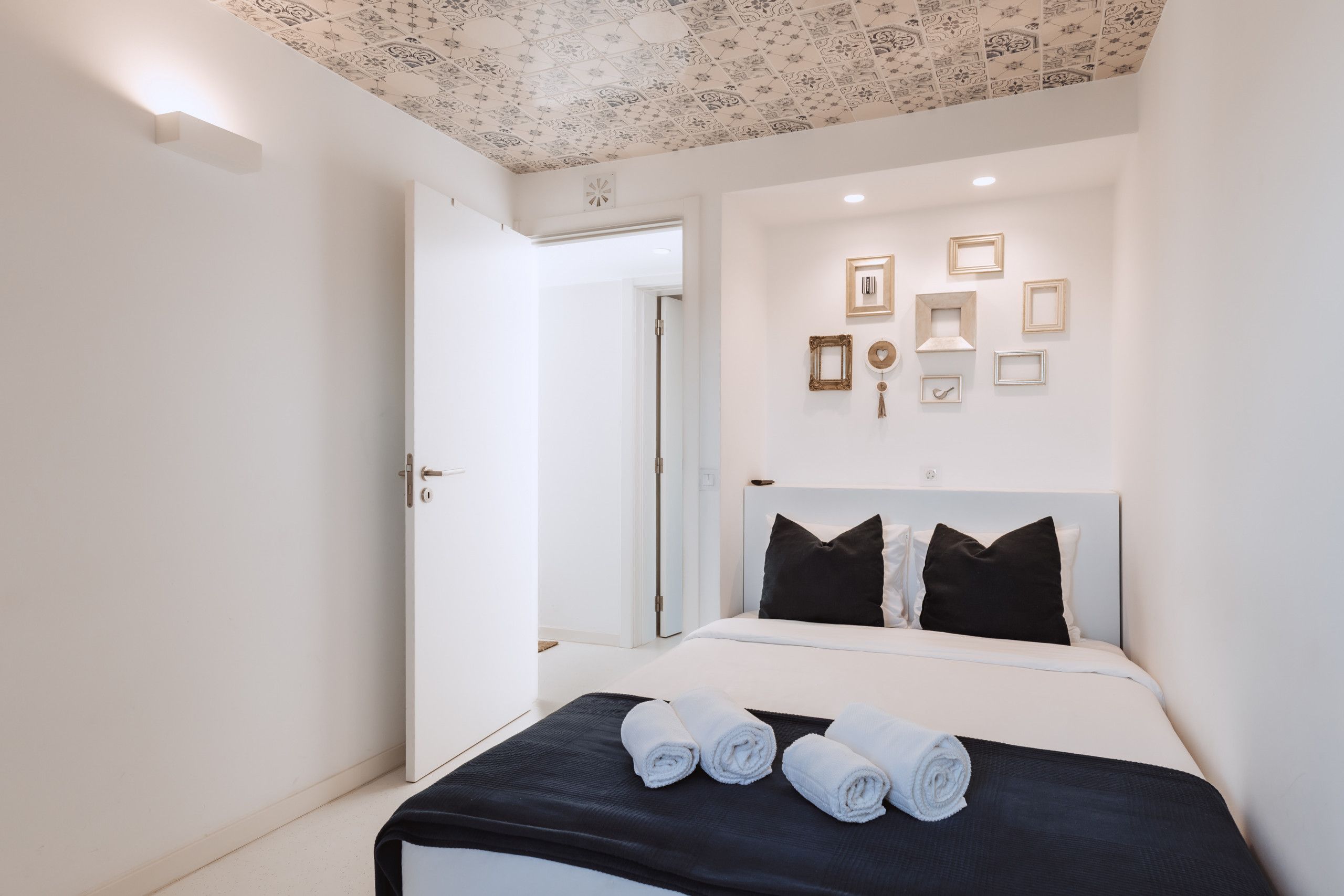 Ein Hotelzimmer mit Bett, schwarzem Kopfteil und Decke mit Muster.