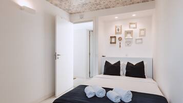 Una habitación de hotel con una cama, cabecera negra y techo con diseño decorativo.