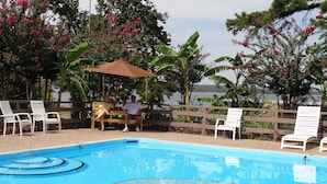 A swimming pool with a wooden deck, lounge chairs, and a wooden fence.