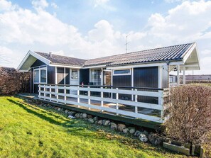 Een tweelaags huis met een witte veranda en een klein terras.