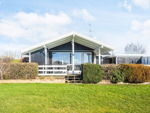 A modern house with a large glass window, a white porch, and a well-maintained lawn. - 6 Person Holiday Home in Ronde (Ronde)