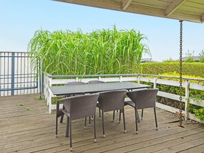 An outdoor patio with a table and chairs, surrounded by a white fence and tall green plants. - 6 Person Holiday Home in Ronde (Ronde)