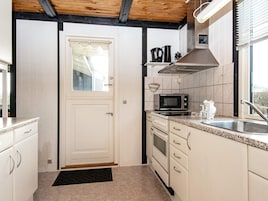 Cocina compacta con muebles blancos, microondas, horno y lavamanos.