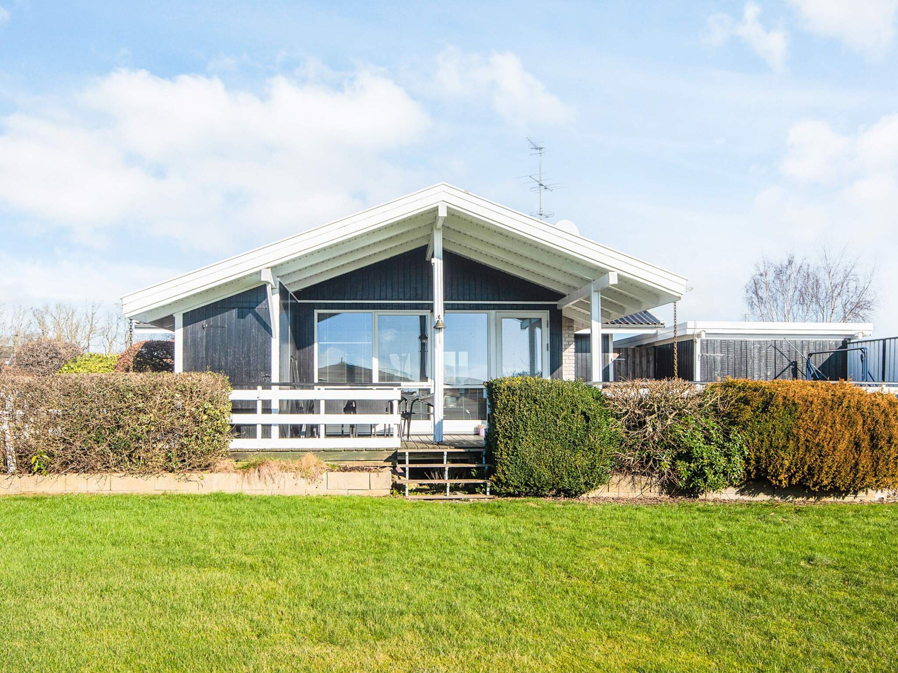 A modern house with a large glass window, a white porch, and a well-maintained lawn.