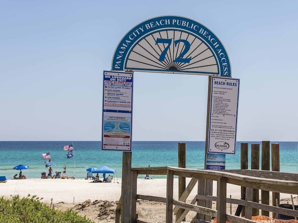 A beach entrance sign with beach rules and safety warnings.