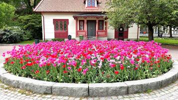 A building with a red-tiled roof and a garden with pink and red tulips.