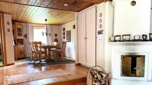 Une pièce au plancher de bois, avec une table et des chaises, une cheminée et un mur orné d’assiettes décoratives.