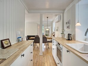 Una cocina moderna con suelo de madera, armarios blancos y una isla central.