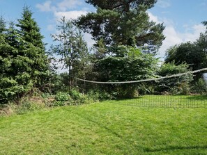 Un área verde con un puente colgante y árboles densos al fondo.